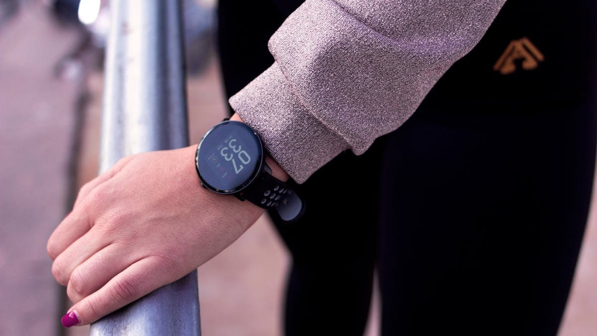 A close-up shot of a hand wearing a digital smartwatch, showcasing modern wearable technology outdoors.
